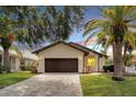 Front view of a single story home with a dark brown garage door and paver driveway at 6208 Spoonbill Dr, New Port Richey, FL 34652