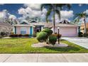 Inviting one-story home with a charming facade, well-manicured lawn, and lush landscaping at 324 Caloosa Palms Ct, Sun City Center, FL 33573