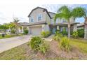 Two-story house with gray siding, light blue shutters, and a stone facade at 14319 Italia Dr, Wimauma, FL 33598