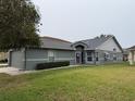 Gray house exterior with a two-car garage and a spacious lawn at 6554 Gentle Ben Cir, Wesley Chapel, FL 33544