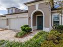 Modern two-car garage with attractive landscaping and an arched entryway at 4155 Barletta Ct, Wesley Chapel, FL 33543