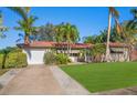 House exterior showcasing a large grassy lawn, driveway, and palm trees at 587 Hillcrest Dr, Largo, FL 33771