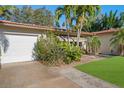 White garage door and lush tropical landscaping at 587 Hillcrest Dr, Largo, FL 33771