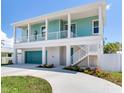 Two-story teal home with white trim, attached garage, and a walkway at 635 115Th Ave, Treasure Island, FL 33706