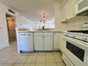 Bright kitchen boasts white cabinets, tile countertops, and a view into the living area at 2991 Flint S Dr # 77-D, Clearwater, FL 33759