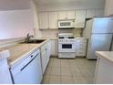 White kitchen with ample cabinetry, tile countertops, and built-in appliances at 2991 Flint S Dr # 77-D, Clearwater, FL 33759