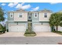 Two-story townhome with attached garages, light-blue and beige exterior, and landscaping at 1003 Starboard Ct, Oldsmar, FL 34677