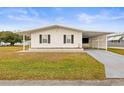 Front view of a white single-wide manufactured home with carport at 36925 Kiowa Ave, Zephyrhills, FL 33542