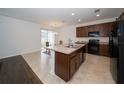 Modern kitchen with dark brown cabinets, an island, and a glass-top dining table at 2941 Adams Cross Dr, Zephyrhills, FL 33540