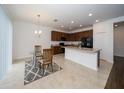 Modern kitchen with dark brown cabinets, an island, and a glass-top dining table at 2941 Adams Cross Dr, Zephyrhills, FL 33540