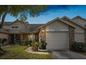 Evening view of tan two-story house with brick accents and attached garage at 6506 Remus Dr, New Port Richey, FL 34653