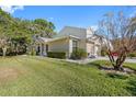 Tan house with green lawn and trees, showcasing a well-maintained exterior at 3203 Audubon Ct, Tarpon Springs, FL 34688