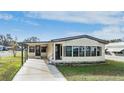 Tan mobile home with carport and landscaped lawn at 35934 Verano Ln, Zephyrhills, FL 33541