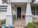 Inviting front entrance with a black door, brick columns, and a tiled porch at 4709 Corsage Dr, Lutz, FL 33558