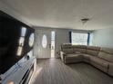 Spacious living room featuring a large TV, comfortable sectional sofa, and gray vinyl plank flooring at 4841 Zodiac Ave, Holiday, FL 34690