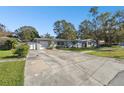 Front view of a Ranch style home with a large driveway and mature trees at 1829 West Dr, Clearwater, FL 33755