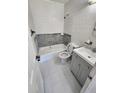 Tiled bathroom featuring a bathtub, toilet, vanity with sink, and neutral gray accents at 4735 22Nd N Ave, St Petersburg, FL 33713