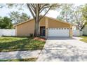 Tan house with white garage door and landscaped lawn at 203 Whisper Lake Rd, Palm Harbor, FL 34683