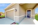 Two-car garage and front entry with a dark brown door at 10827 High Noon Trl, Parrish, FL 34219