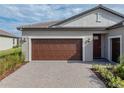 Home's exterior showcases a brown garage door and a brick paved driveway at 12626 Tahitian Pearl Cir, Parrish, FL 34219