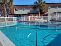 Community pool surrounded by palm trees and white picket fence and chairs for lounging at 1330 70Th N St, St Petersburg, FL 33710