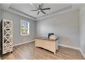 Spacious home office with wood-look tile floor, desk, and window with plantation shutters at 13307 Fawn Lily Dr, Riverview, FL 33579