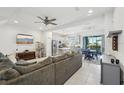Open-concept living room features a large gray sofa, modern ceiling fan, and tile flooring at 6324 Camino Dr, Apollo Beach, FL 33572