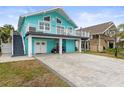 Two-story teal house with a large driveway and a golf cart at 17706 1St E St, Redington Shores, FL 33708