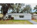 Charming single story home with a white exterior and mature landscaping at 1833 Knollwood Dr, Holiday, FL 34690