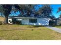 White house with green lawn, driveway, and mature trees at 1833 Knollwood Dr, Holiday, FL 34690