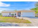 Tan house with a white garage door, landscaping, and a paved driveway at 2109 Elmwood Ct, Plant City, FL 33563