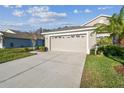 Tan house with a two-car garage and lush landscaping at 2932 Tanglewylde Dr, Land O Lakes, FL 34638