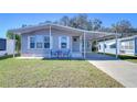 Gray mobile home with carport, landscaped lawn, and seating area at 4853 Blanco Dr, Zephyrhills, FL 33541