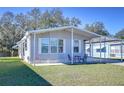 Gray mobile home with carport, landscaped lawn, and seating area at 4853 Blanco Dr, Zephyrhills, FL 33541