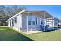 Gray mobile home with carport, landscaped lawn, and seating area at 4853 Blanco Dr, Zephyrhills, FL 33541
