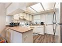 Kitchen with laminate flooring, white cabinets, and a breakfast bar at 7029 Oakwood Dr, New Port Richey, FL 34652