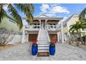 Two-story home with white exterior, inviting front porch, and a meticulously landscaped yard at 12112 Lagoon Ln, Treasure Island, FL 33706