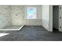 Bathroom with marble shower, dark gray floor tiles, and a window at 3424 Ohio Ave, Tampa, FL 33611