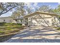 Tan house exterior with a large white garage door and landscaped yard at 4320 63Rd N St, Kenneth City, FL 33709