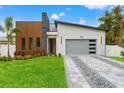 Modern home with stone and wood accents, gray garage door, and landscaped lawn at 1905 W Erna Dr, Tampa, FL 33603