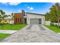 Modern home with stone and wood accents, gray garage door, and landscaped lawn at 1905 W Erna Dr, Tampa, FL 33603