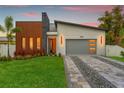 Modern home with stone and wood accents, gray garage door, and landscaped lawn at 1905 W Erna Dr, Tampa, FL 33603