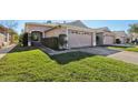 Beige house with a two-car garage and well-maintained lawn at 31447 Shaker Cir, Wesley Chapel, FL 33543