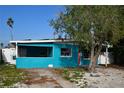 Quaint teal home with a red door and mature tree at 540 Marlyn Way, Madeira Beach, FL 33708