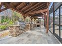 Outdoor kitchen with grill and pizza oven under a wood pergola at 4825 Scott Rd, Lutz, FL 33558