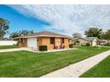 Single-story home with a brown exterior, nicely landscaped yard, and attached garage at 153 Sunward Ave, Palm Harbor, FL 34684