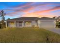 House exterior at dusk showcasing a beige exterior, gray roof, and landscaping at 7258 Bridgeport Ln, Englewood, FL 34224
