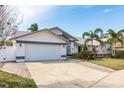 Front view of a house with a white exterior, two car garage and palm trees at 1028 Wyndham Way, Safety Harbor, FL 34695