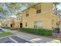 Tan two-story townhome with manicured hedges and landscaping at 37650 Aaralyn Rd, Zephyrhills, FL 33542