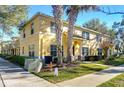 Tan two-story townhome with palm trees and manicured landscaping at 37650 Aaralyn Rd, Zephyrhills, FL 33542